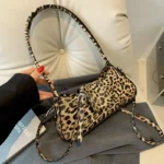 Petit sac à main léaopard à bandoulière présenté sur un canapé
