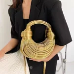 Sac à main doré luxe de soirée desig noué tenu par une femme