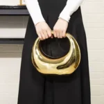 Sac à main doré soirée avec anse rond tenue à la main par une femme