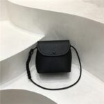 Mini sac à main carré au design compact présenté sur un décor en fond blanc