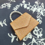 Mini sac à main élégant et carré en paille sur un fond bleu avec des fleurs