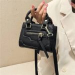 Mini sac à main noir design et élégant porté à la main par une femme