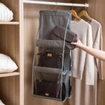 Rangement sac à main gris en six compartiments, accroché sur une barre de penderie