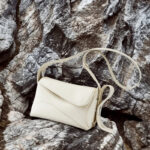 Sac à main beige élégant et raffiné en cuir posé sur des rochers