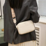 Sac à main beige petit format à bandoulière, porté par une femme de dos.