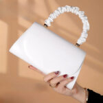 Sac à main blanc épuré et chic blanc présenté par une main de femme