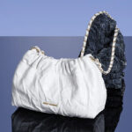 Sac à main blanc souple et chic posé sur un support gris