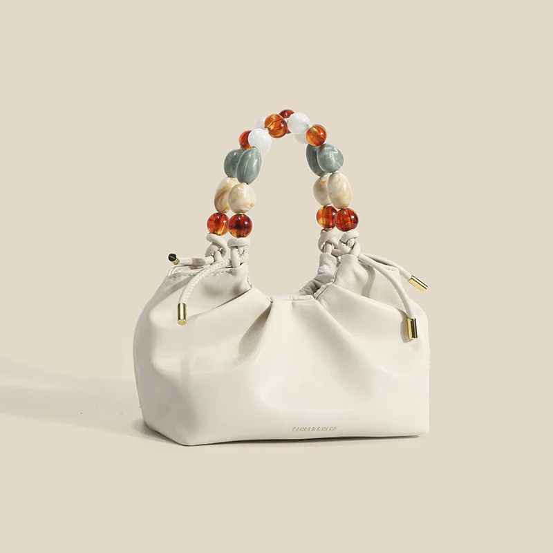 Sac à main blanc souple en cuir sur fond crème