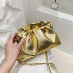 Sac à main doré élégant avec bandoulière présenté par une main de femme
