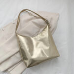 Sac à main doré luxueux et minimaliste posé sur une veste blanche