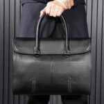 Sac à main homme cuir noir chic et sophistiqué tenu à la main