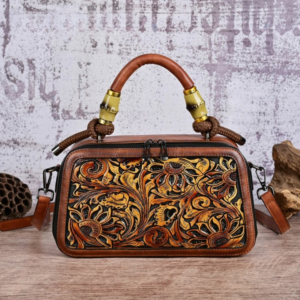 Sac à main marron à bandoulière en simili cuir motif floral, sur un fond gris et marron.