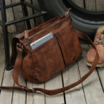 Sac à main marron à bandoulière style vintage en cuir, posé sur le plancher