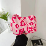 Sac à main rose décontracté avec motifs léopard présenté par une main de femme