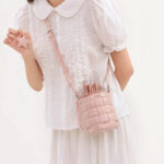 Sac à main rose sophistiqué et original porté à l'épaule par une jeune femme
