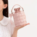 Sac à main rose sophistiqué et original présenté par une main de femem