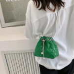 Sac à main vert élégant matelassé en similicuir porté à l'épaule e vue de dos