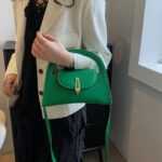 Sac à main vert raffiné et tendance, porté par une femme.