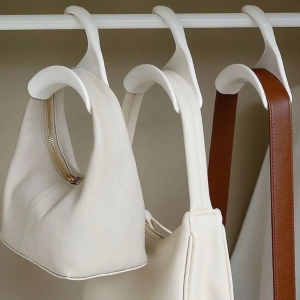 accroche-sac-main-design-col-cygne-03 Trois accroches sac à main design col de cygne suspendus à une penderie avec des sacs à mains