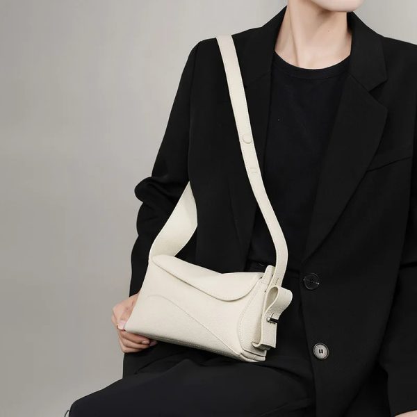 sac-main-beige-elegant-raffine-cuir-03 Sac à main beige élégant et raffiné en cuir, porté par une femme avec un haut noir.