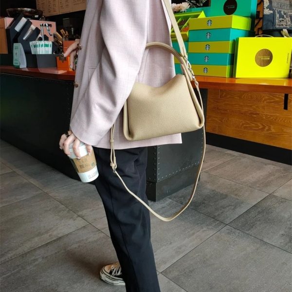 sac-main-beige-simili-cuir-bandouliere-large-04 Sac à main beige en simili cuir avec bandoulière large, porté à l'épaule dans un magasin