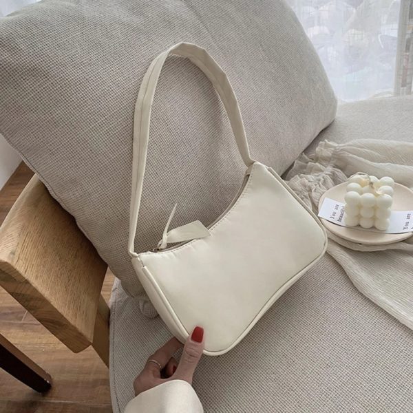 sac-main-blanc-simple-bandouliere-01 Sac à main blanc simple avec bandoulière présenté sur une chaise de couleur crème