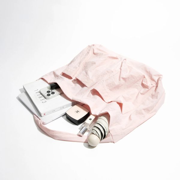 sac-main-rose-souple-decontracte-04 Sac à main rose souple et décontracté posé sur fond blanc avec accessoire à l'intérieur