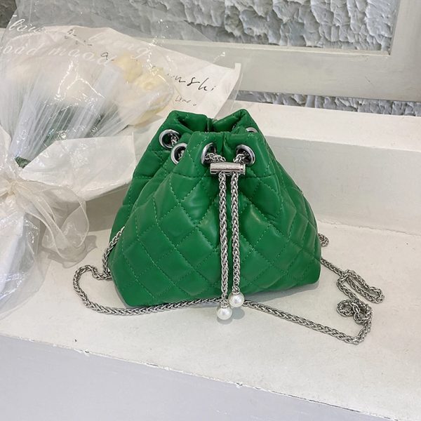 Sac à main vert élégant matelassé en similicuir posé sur une étagère blanche